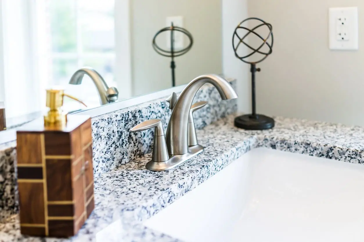 Bathroom sink with chrome faucet and soap dispenser.